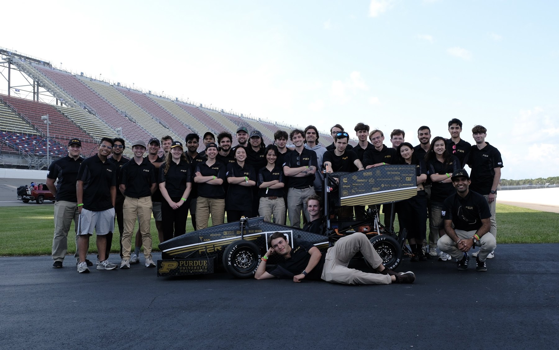 The 2025 Purdue Electric Racing team with their car on the front straight at competition